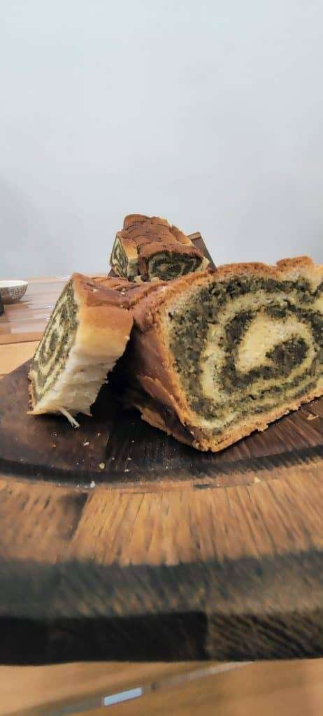 Aufgeschnittener Germstrudel mit dunkler Fülle auf einem runden Holzbrett